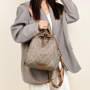 Detail of khaki quilted nylon backpack with brown leather trim and zipper closure