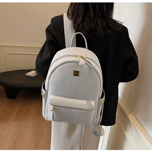 Close-up of light blue crocodile pattern backpack with golden metal logo and zippers