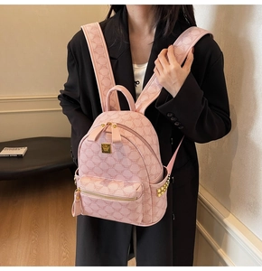 Detail of pink student backpack with golden studs, letter print, and metal brand plate