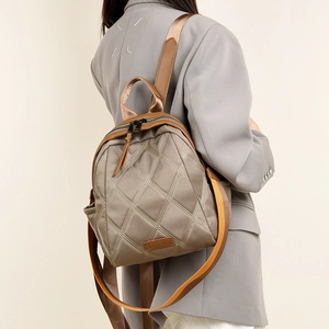 Close-up of quilted khaki nylon backpack with contrast stitching and brand logo