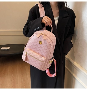 Detailed close-up of a pink synthetic leather backpack with golden studs and metal logo