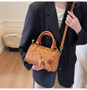 Detail of brown barrel bag with bear print and cute leather bear charm on model