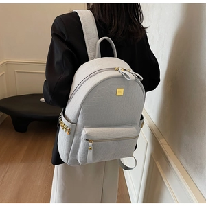 Side view of woman wearing blue faux crocodile leather backpack with gold rivets
