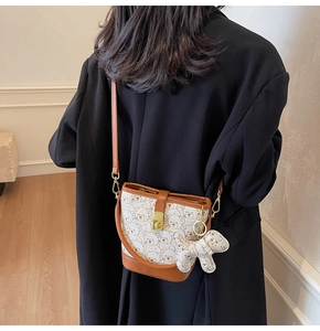 Detail of bear print bucket bag with golden lock and charm on black blazer