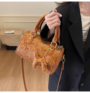 Detail of orange barrel bag with cute bear print, dual handles and golden hardware