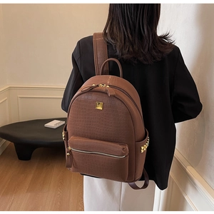 Detail of brown crocodile pattern backpack with golden studs and metal logo plate