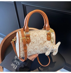 Detail view of the retro bear pattern on the white cylindrical barrel handbag with long strap
