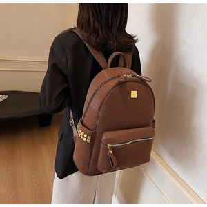 Brown crocodile texture leather backpack with gold rivets and top handle shown on model