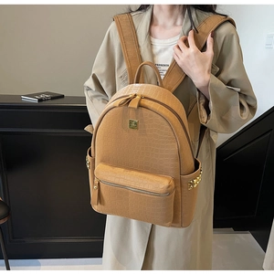 Close-up of khaki faux leather backpack featuring crocodile texture and gold hardware