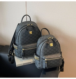Detail view of grey monogram backpacks with gold rivets and metallic butterfly logo