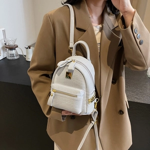 Chic white crocodile embossed mini backpack with gold hardware worn by a model
