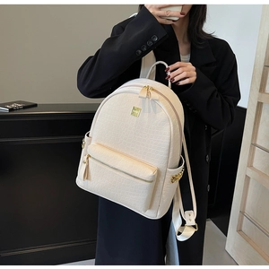 Detailed close-up of beige crocodile pattern faux leather backpack with gold rivets