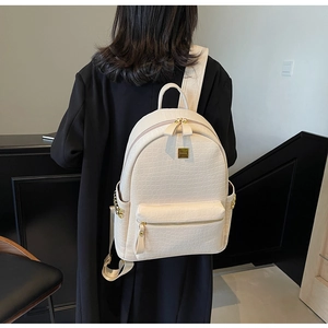 Detailed back view of white crocodile pattern backpack with gold hardware on a model