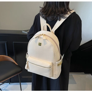 Detail view of cream crocodile textured leather backpack with gold rivets and zippers