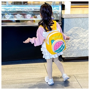 Detail of yellow kids backpack with dinosaur print and watermelon shaped front pocket