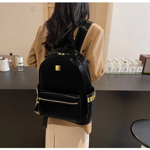 Detail view of black crocodile pattern backpack with golden studs and metal zipper hardware