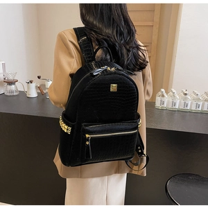 Detail of black faux leather backpack with crocodile texture and gold stud accents
