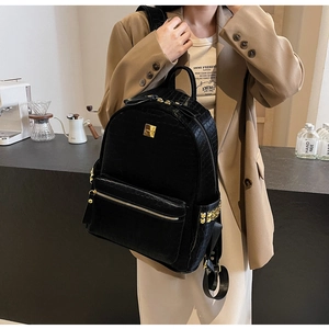 Detail of black crocodile embossed backpack featuring gold studs and luxury metal hardware