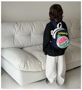 Detail of cartoon dinosaur and watermelon print on navy blue toddler backpack