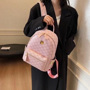 Pink women backpack with monogram pattern and gold metal hardware logo in indoor setting