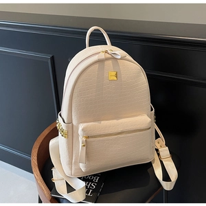 Detail of creamy white faux crocodile skin texture and gold hardware on fashion backpack
