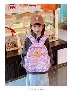 Détail d'un sac à dos violet à motifs de dessins animés porté par une petite fille