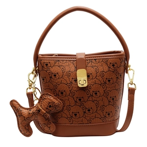 Brown bucket bag with bear print, gold lock, puppy charm, and adjustable shoulder strap