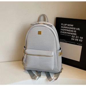 Detail of light grey crocodile pattern backpack with gold hardware and side rivets