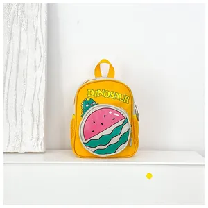 Detail of a yellow toddler backpack featuring a green cartoon dinosaur and watermelon pocket
