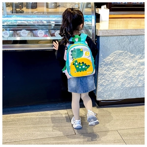 Side view of a cute cartoon dinosaur backpack on a child in a lifestyle setting