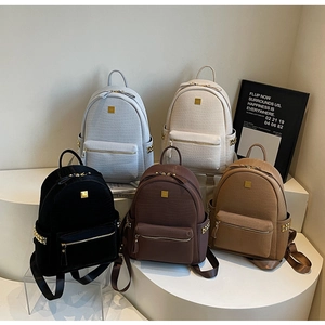 Detail view of five textured crocodile pattern backpacks in various fashion colors