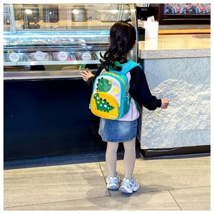 Rear view of a child wearing the colorful 3D dinosaur backpack with side mesh pockets