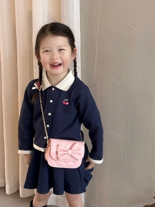 Détail d'un sac à bandoulière matelassé rose avec nœud et chaîne dorée sur un enfant