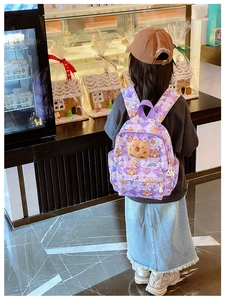Vue de dos d'un enfant portant un sac à dos violet avec imprimés Capybara et poupée ours 3D