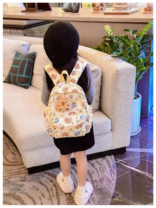 Détail d'un sac à dos enfant Capybara avec pendentif en peluche et imprimé dessin animé jaune