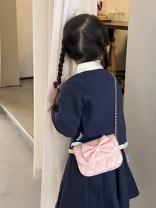 Sac bandoulière rose matelassé avec grand nœud, porté par un enfant, vue de dos