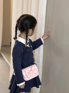 Détail du sac à bandoulière rose matelassé avec nœud et chaîne sur robe marine