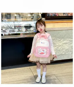 Pink cartoon kids backpack with clear PVC pocket featuring a cute plush doll on a young model