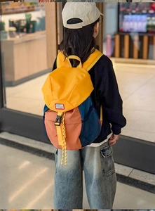Detailed view of child wearing colorful contrast outdoor backpack with buckle closure