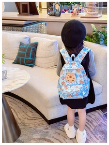 Détail d'un enfant portant un sac à dos bleu à carreaux avec imprimés capybara