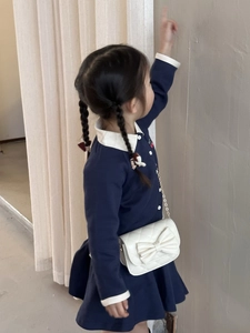 Détail d'une robe en tricot bleu marine pour fille avec col Claudine et sac à bandoulière