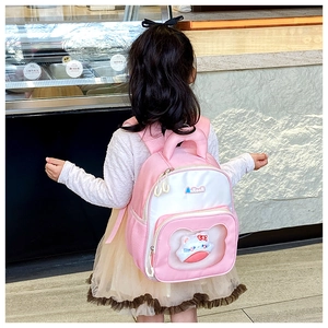 Rear view of a pink kids backpack with a cute cartoon cat doll in the front pocket