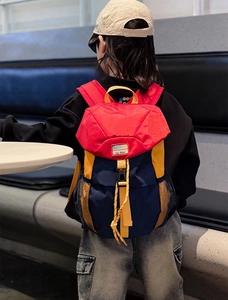Detail view of child wearing contrast color backpack with buckles and mesh pockets