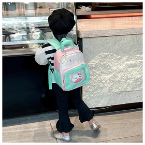 Pink and green schoolbag with transparent window and cute white plush cat doll on model