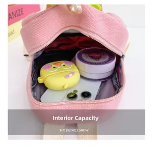 Internal capacity of pink mini backpack showing phone, earbuds case and cosmetics