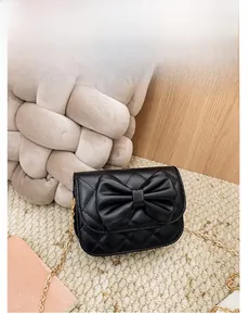 Vue détaillée du sac matelassé noir pour fille avec grand nœud et bandoulière dorée