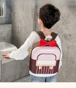 Pink and brown hard shell kids backpack with red bow, back view on a child model