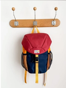 Detail of color-block kids backpack with red top flap and navy body on a hook