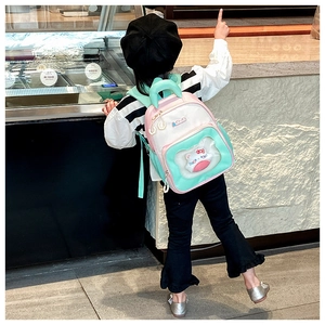 Detail of mint green and pink kid's backpack with cute plush doll in transparent pocket