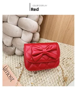 Détail du sac enfant matelassé rouge avec grand nœud décoratif et chaîne dorée